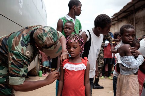 JOOST DE RAEYMAEKER: epaselect epa05164601 A Angolan military administers a yellow fever vaccine to a child at 'Quilometro 30' market, Luanda, Angola, 16 February 2016. This market in the Angolan capital was considered the center of the yellow fever outbreak killing 51 people