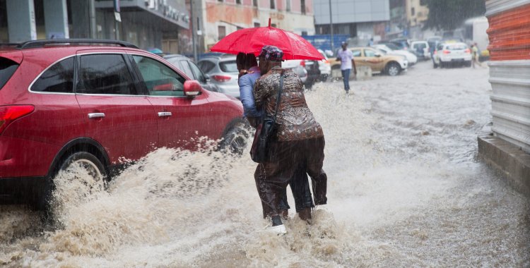 MICHAEL KAPPELER: epa04141711 A man carries another across a flooded street after heavy rainfalls in Luanda, Angola, 26 March 2014. It is the first heavy rain at the start of the rainy season. Germany Foreign�Minister Steinmeier is on a three-day trip to the West African c